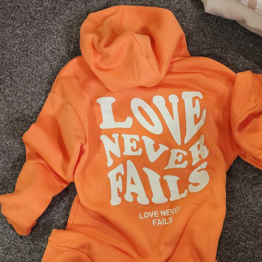 Orange Hoodie with 'Love Never Fails' Print